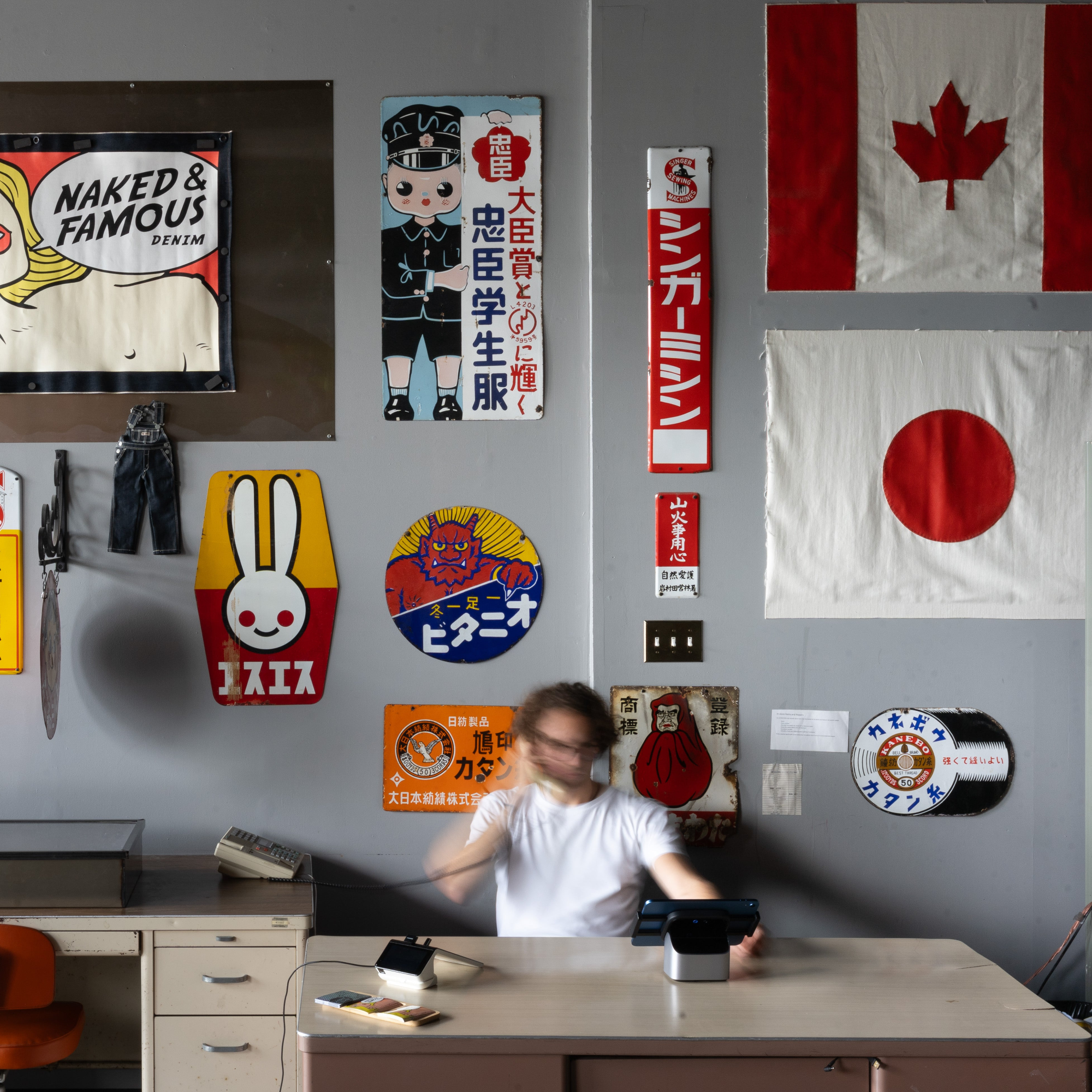 Person sitting at a desk in a room with various posters and flags on the wall.